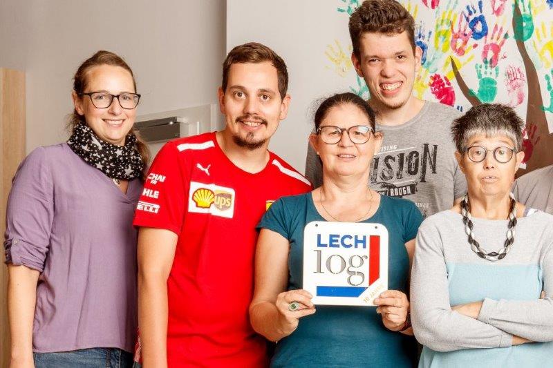 Eine Frau arbeitet an einem Plakt und wird von einem Mann unterstützt