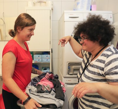 Zwei Frauen befüllen eine Waschmaschine.