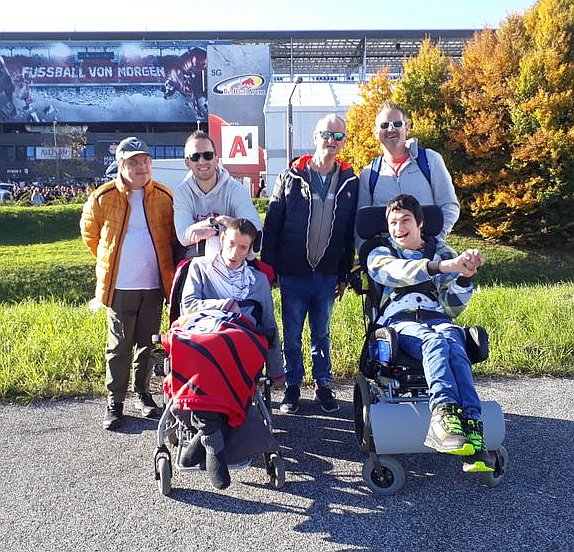 Sechs Männer stehen vor einem Fußballstadion