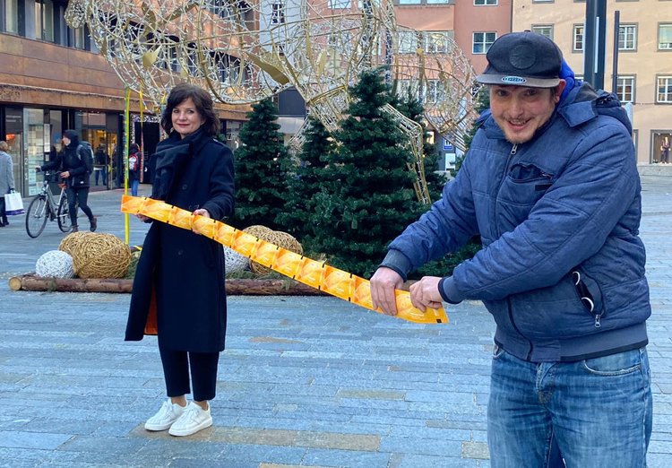 Eine Frau und ein Mann stehen am Stadtplatz und halten Eintrittskarten in der Hand.