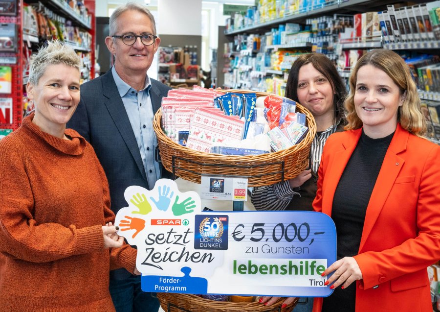 Vier Personen stehen in einem Supermarkt und halten einen Spendenscheck: Spar spendet 5000 Euro zugunsten der Lebenshilfe