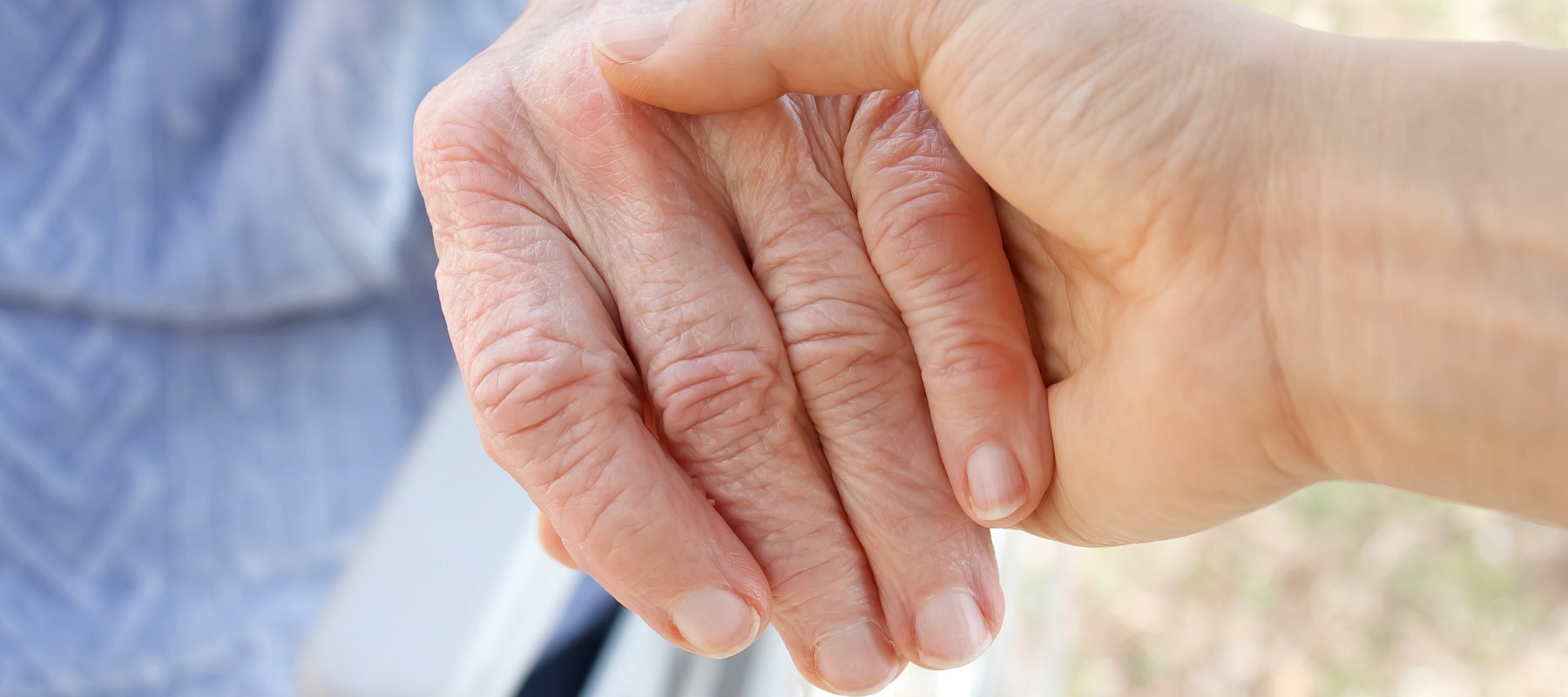 Nahaufnahme: Eine Hand hält die Hand eines alten Menschen