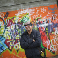 Ein junger Mann vor einem bunten Graffiti.