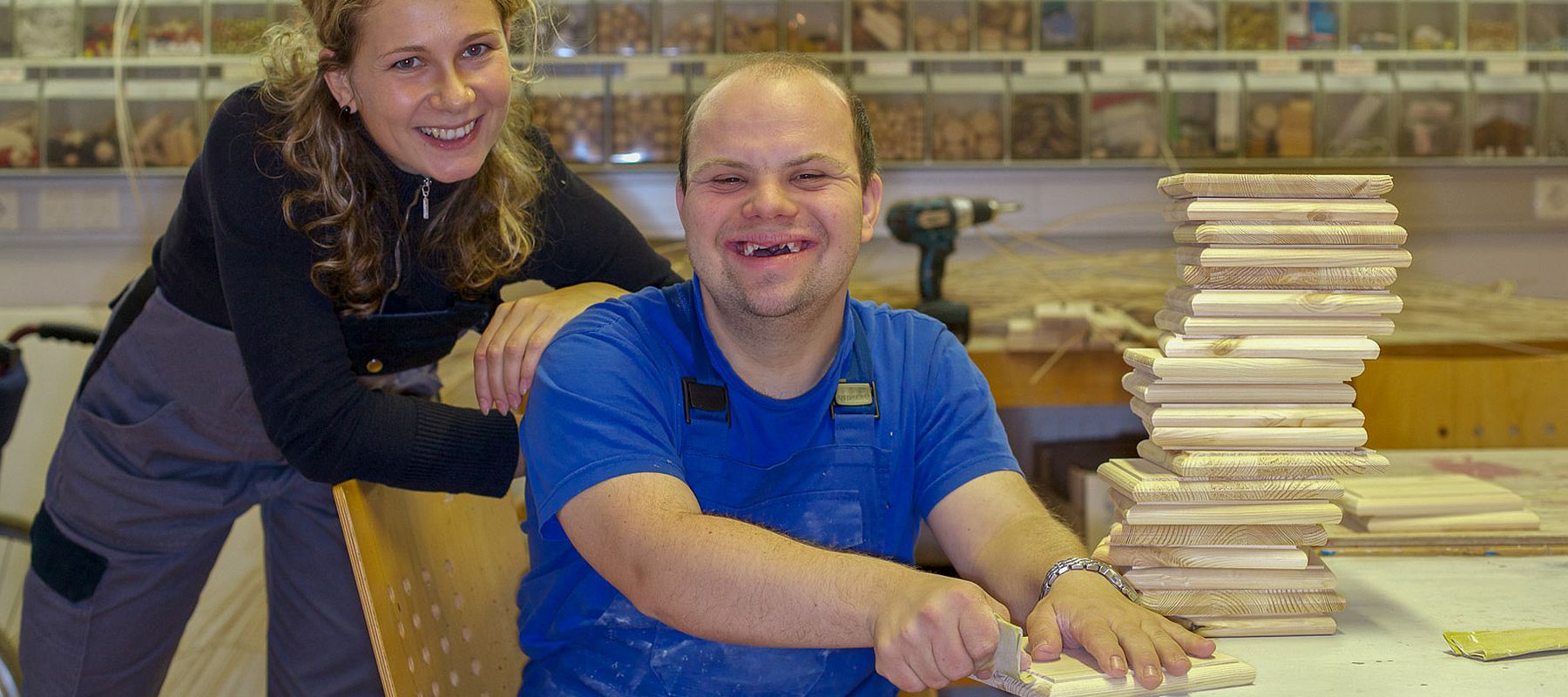 Eine junge Frau und ein junger Mann mit Down-Syndrom in einer Tischlerei.