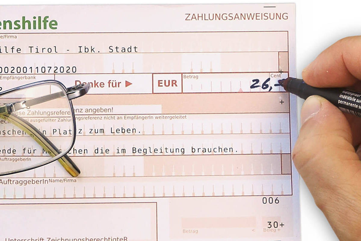 Jemand füllt einen Spendenzahlschein aus und schreibt 26 Euro in das Betragsfeld