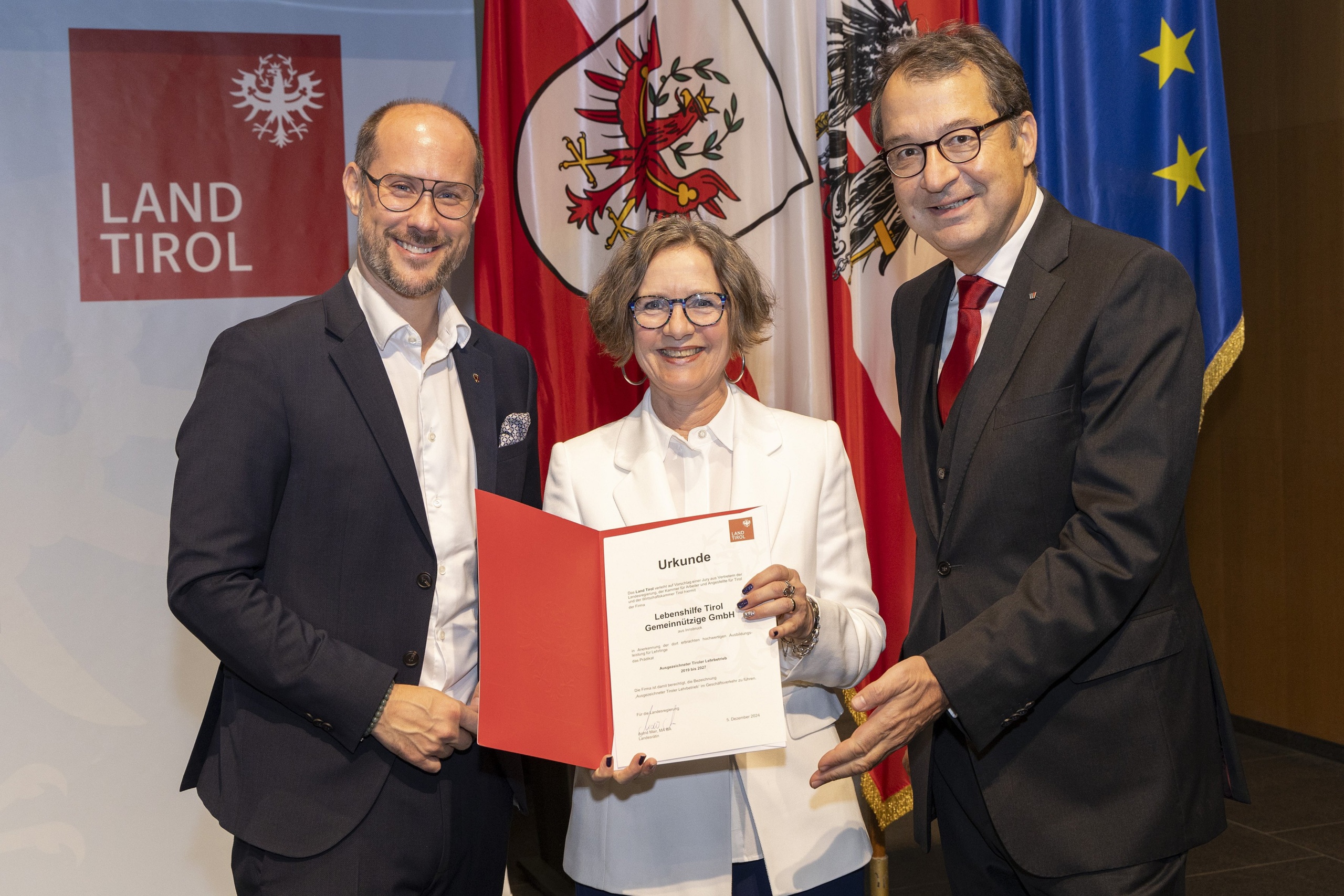 Frau bekommt von zwei Männern eine Auszeichnung